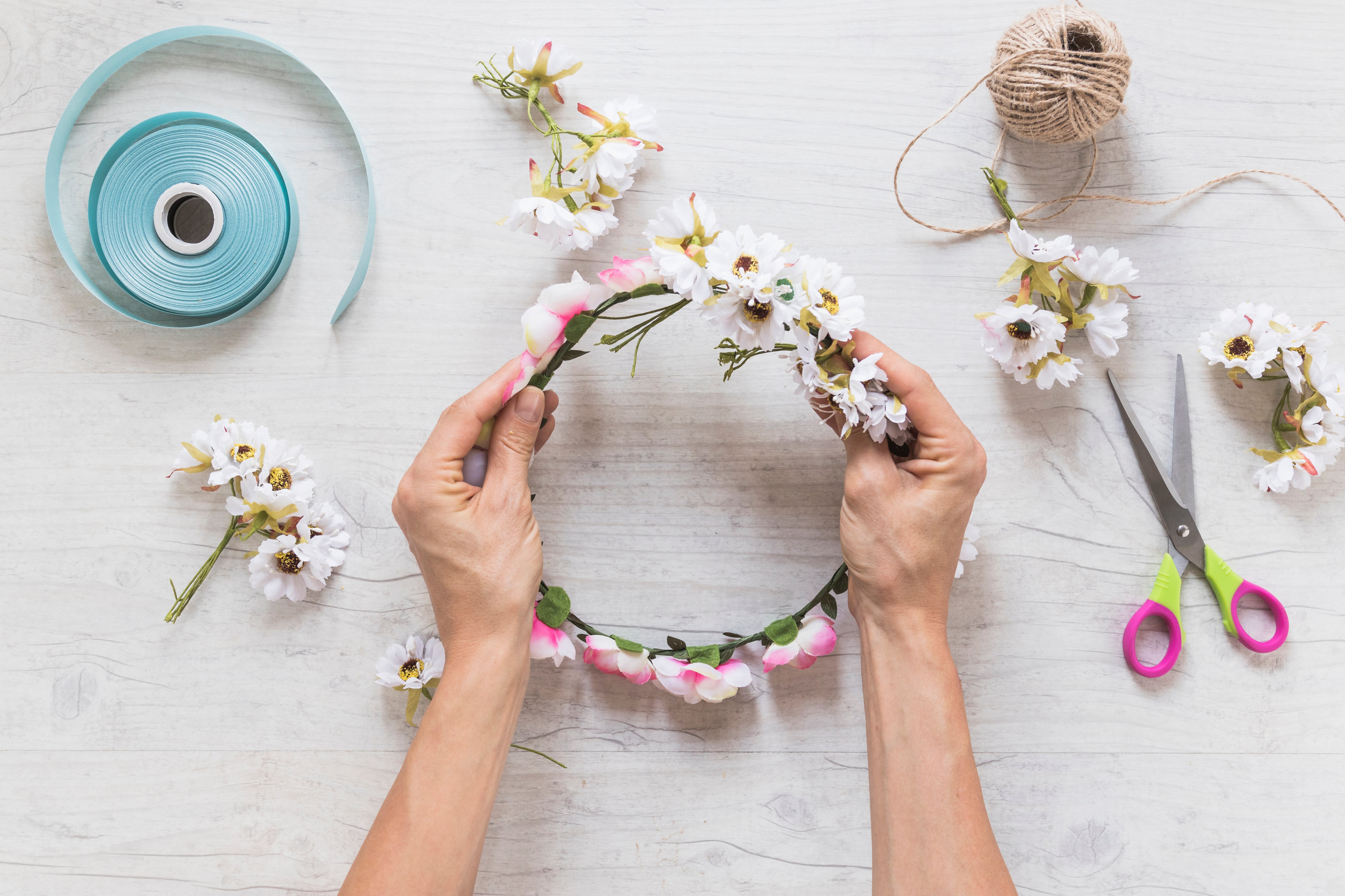 close-up-person-holding-fake-floral-wreath-textured-backdrop
